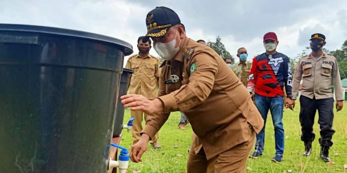 DISIPLIN: Bupati Kotim, H Halikinnor menerapkan prokes dengan mencuci tangan saat melakukan kunjungan ke Dusun Muara Ubar, Kecamatan Telawang, Selasa (27/7). (FOTO: HUMAS UNTUK KALTENG POS)