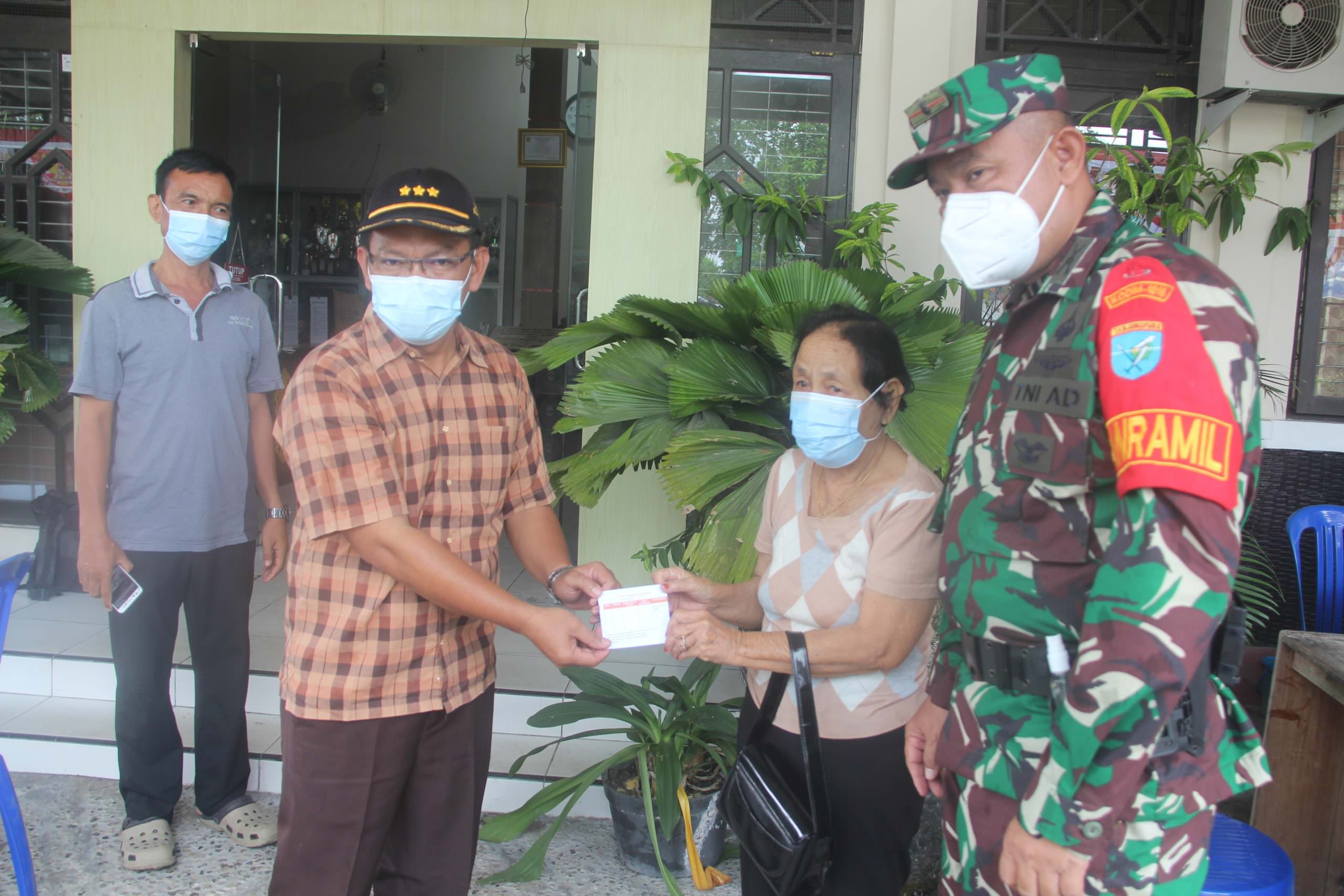 MENYERAHKAN: Camat Jekan Raya Sri Utomo (dua dari kiri) saat menyerahkan tanda kartu sudah mengikuti vaksin kepada salah seorang warga di Kantor Kecamatan Jekan Raya, Minggu (22/8). (foto: PATHUR/KALTENG POS)