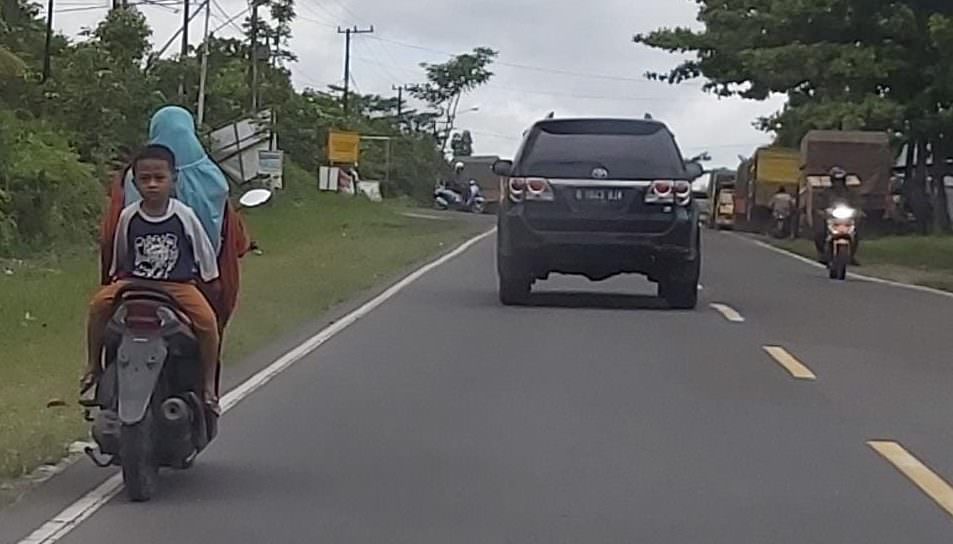 BERBAHAYA : Pengendara motor ini terbilang nekat membonceng anaknya dengan posisi sangat berbahaya di jalan menuju Kumai, Minggu (5/9). (FOTO: SONY/KALTENG POS )