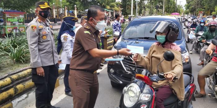 BAGI MASKER: Kasi Intel Kejari Kobar Jul Indra Nasution ketika membagikan masker kepada pengendara yang melintas, Senin (20/9). (FOTO: SONY/KALTENG POS)