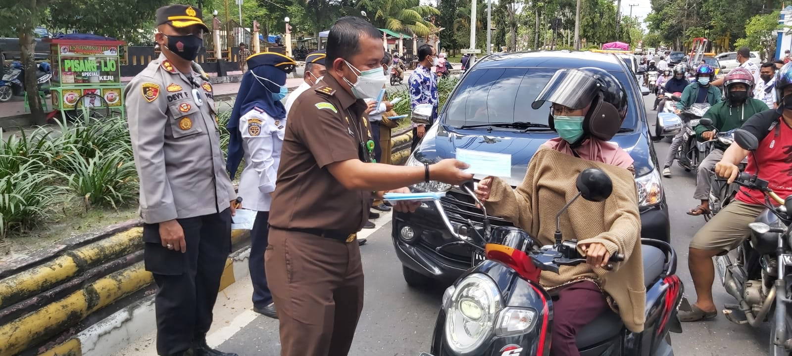 BAGI MASKER: Kasi Intel Kejari Kobar Jul Indra Nasution ketika membagikan masker kepada pengendara yang melintas, Senin (20/9). (FOTO: SONY/KALTENG POS)