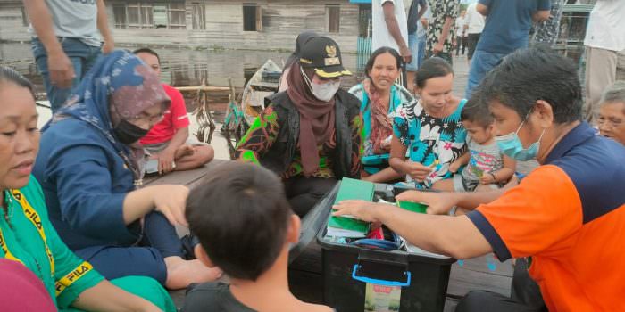 KUNJUNGAN KERJA: Wabup Kotim, Irawati (pakai masker putih) memastikan kondisi kesehatan warga yang ada di wilayah terdampak banjir, Rabu (15/9). (FOTO: SAMPIT - Pemerintah Kabupaten Kotawaringin Timur terus melakukan upaya preventif terhadap kesehatan warga yang terdampak banjir. Hal itu dilakukan untuk mengetahui kondisi kesehatan, sehingga jika ada penyakit membaha-yakan, warga bisa langsung dirujuk ke fasilitas kesehatan. Wakil Bupati (Wabup) Kotim, Irawati bersama tim BPBD, ketua Ikatan Bidan Indonesia (IBI) memberikan pelayanan kesehatan, dan pengobatan bagi warga yang mengalami ganguan kesehatan di Dusun Muara Ubar, dan Desa Tanah Putih, Kecamatang Telawang, Rabu (15/9). Selain itu, kedatangan mantan anggota DPRD Provinsi Kalteng itu bersama rombongan juga memberikan bantuan so-sial (bansos) berupa sembako kepada masyarakat di dua desa tersebut. “Kemarin saya langsung melihat kondisi kesehatan warga yang terdampak banjir. Saya apresiasi petugas kesehatan di lapangan selalu stanby memberikan pe-layanan kesehatan,” kata Irawati. Dia meminta, agar petugas kesehatan yang berada di lapangan untuk selalu rutin melakukan pemantauan terhadap kondisi warga. Sebab dalam situasi seperti ini tentu sewaktu - waktu sejumlah penyakit seperti demam, diare, dan lain sebagainya, bisa menyerang sehingga sangat penting untuk terus melakukan pemantauan terhadap kondisi kesehatan warga. “Tujuan saya sering turun ke lokasi banjir untuk memastikan kondisi warga, mengingat saat ini masyarakat terdampak sedang mengalami musibah dan sudah selayaknya untuk dibantu serta diperhatikan,” tegasnya. Kepada masyarakat, Irawati beperpesan jika ada keluhan kesehatan bisa segera melapor atau menghubungi petugas kesehatan yang ada di lapangan, untuk bisa dilakukan pelayanan kesehatan dan mari sama - sama berdoa agar masalah ini bisa segera selesai. (sli/ans) )