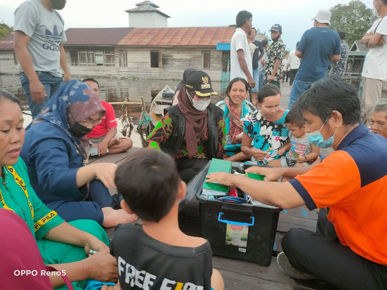 KUNJUNGAN KERJA: Wabup Kotim, Irawati (pakai masker putih) memastikan kondisi kesehatan warga yang ada di wilayah terdampak banjir, Rabu (15/9). (FOTO: SAMPIT - Pemerintah Kabupaten Kotawaringin Timur terus melakukan upaya preventif terhadap kesehatan warga yang terdampak banjir. Hal itu dilakukan untuk mengetahui kondisi kesehatan, sehingga jika ada penyakit membaha-yakan, warga bisa langsung dirujuk ke fasilitas kesehatan. Wakil Bupati (Wabup) Kotim, Irawati bersama tim BPBD, ketua Ikatan Bidan Indonesia (IBI) memberikan pelayanan kesehatan, dan pengobatan bagi warga yang mengalami ganguan kesehatan di Dusun Muara Ubar, dan Desa Tanah Putih, Kecamatang Telawang, Rabu (15/9). Selain itu, kedatangan mantan anggota DPRD Provinsi Kalteng itu bersama rombongan juga memberikan bantuan so-sial (bansos) berupa sembako kepada masyarakat di dua desa tersebut. “Kemarin saya langsung melihat kondisi kesehatan warga yang terdampak banjir. Saya apresiasi petugas kesehatan di lapangan selalu stanby memberikan pe-layanan kesehatan,” kata Irawati. Dia meminta, agar petugas kesehatan yang berada di lapangan untuk selalu rutin melakukan pemantauan terhadap kondisi warga. Sebab dalam situasi seperti ini tentu sewaktu - waktu sejumlah penyakit seperti demam, diare, dan lain sebagainya, bisa menyerang sehingga sangat penting untuk terus melakukan pemantauan terhadap kondisi kesehatan warga. “Tujuan saya sering turun ke lokasi banjir untuk memastikan kondisi warga, mengingat saat ini masyarakat terdampak sedang mengalami musibah dan sudah selayaknya untuk dibantu serta diperhatikan,” tegasnya. Kepada masyarakat, Irawati beperpesan jika ada keluhan kesehatan bisa segera melapor atau menghubungi petugas kesehatan yang ada di lapangan, untuk bisa dilakukan pelayanan kesehatan dan mari sama - sama berdoa agar masalah ini bisa segera selesai. (sli/ans) )