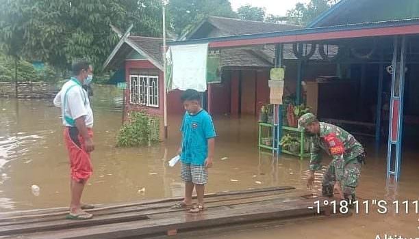 BANTU WARGA: Babinsa Koramil 1015-18/Seruyan Hulu Serka Singgih membantu warga di wilayah binaannya yang rumahnya terendam air di Desa Tumbang Manjul, Kamis (2/8). (FOTO: PENREM 102/Pjg)