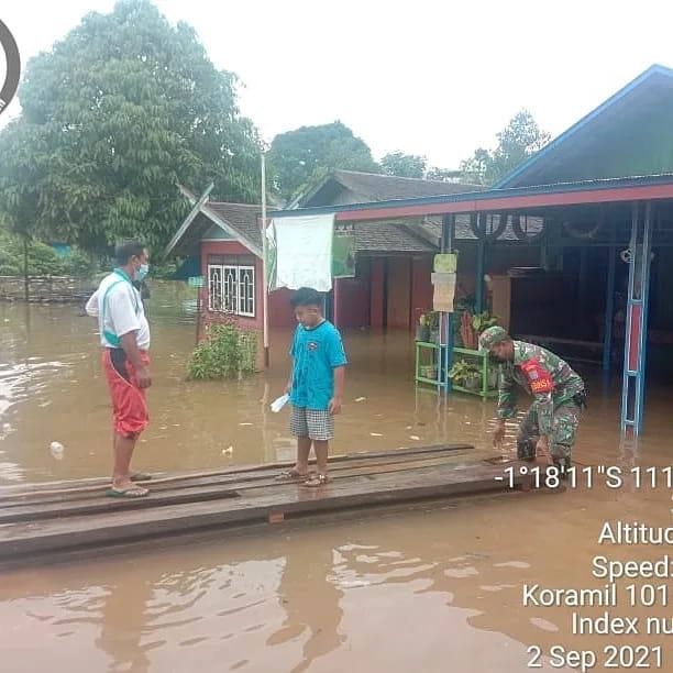 BANTU WARGA: Babinsa Koramil 1015-18/Seruyan Hulu Serka Singgih membantu warga di wilayah binaannya yang rumahnya terendam air di Desa Tumbang Manjul, Kamis (2/8). (FOTO: PENREM 102/Pjg)