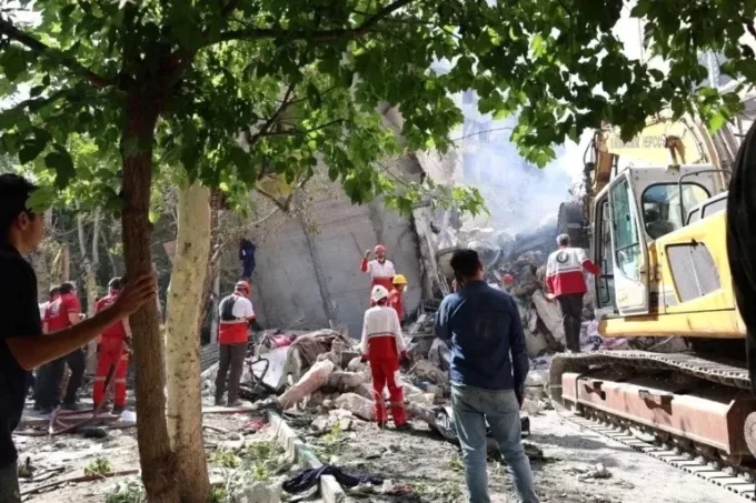 Petugas penyelamat bekerja di lokasi bangunan yang rusak akibat serangan udara Israel, di Teheran, Iran.